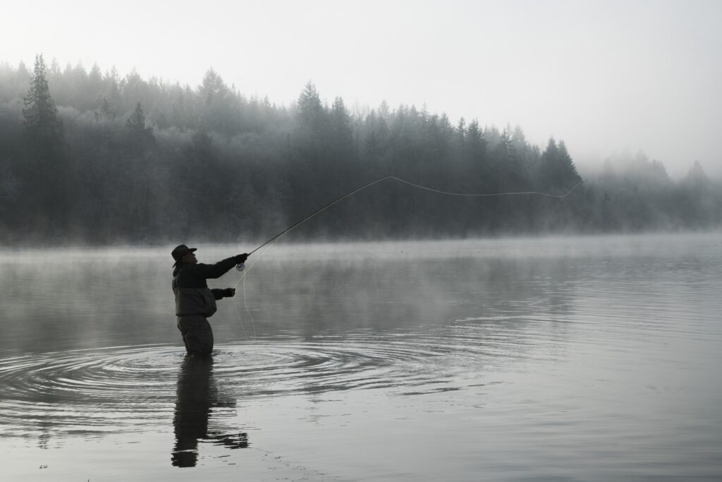 Angler skillfully stillwater fly fishing in a serene setting, surrounded by natural beauty.
